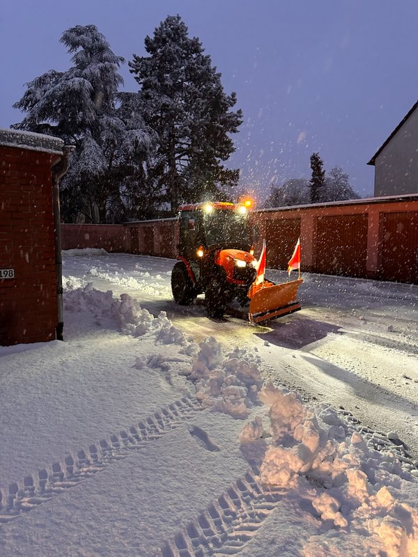 Winter_01 Ein verschneiter Garagenhof, der von einem Schneepflug freigeräumt wird